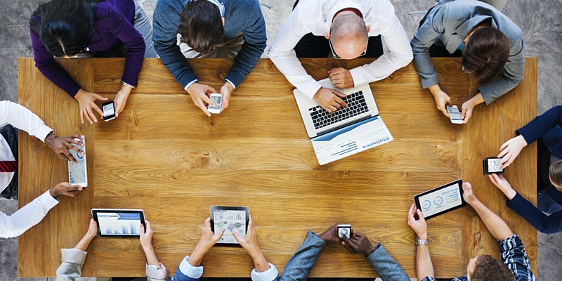 Aeriel shot of a group of people sat around a table with mobile devices