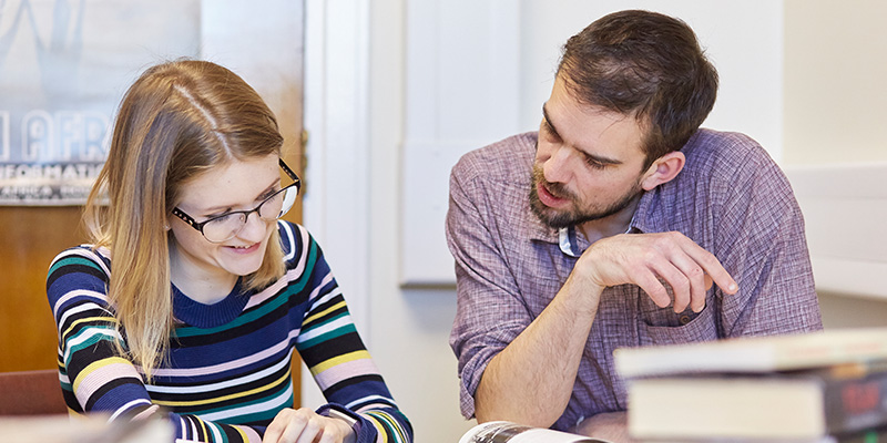 Two people reviewing a piece of text.