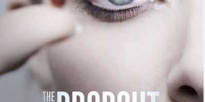 The Dropout - woman in close-up holds tiny pill by her eye