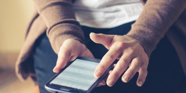 Woman's hands holding smartphone in lap