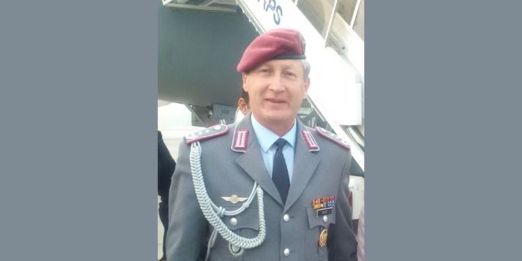A man wearing a beret and a grey military suit