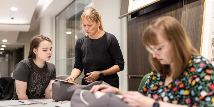 Three people looking at objects in Special Collections at the University of Leeds