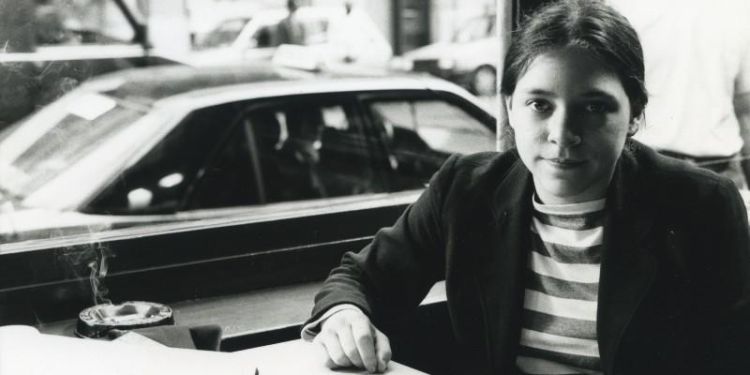 Young woman sitting at a table next to a window