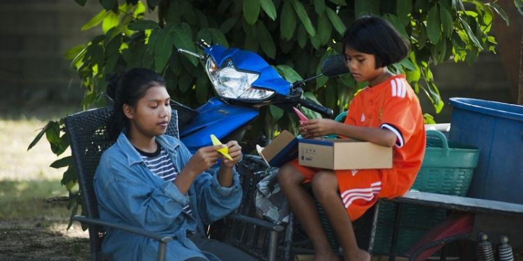 Two Thai children sitting playing and doing crafts