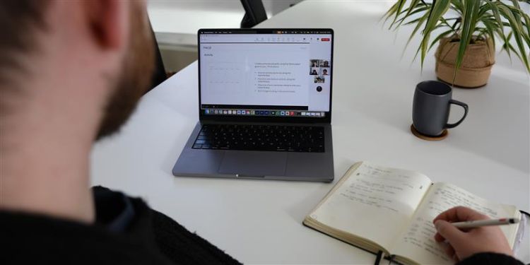 Someone at a laptop taking notes from an online webinar