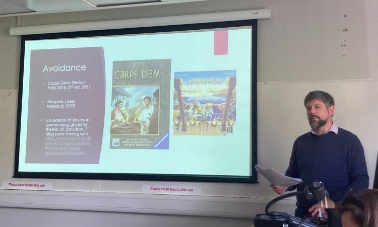 Owen Hodkinson speaking at a colloquium with presentation screen on the wall