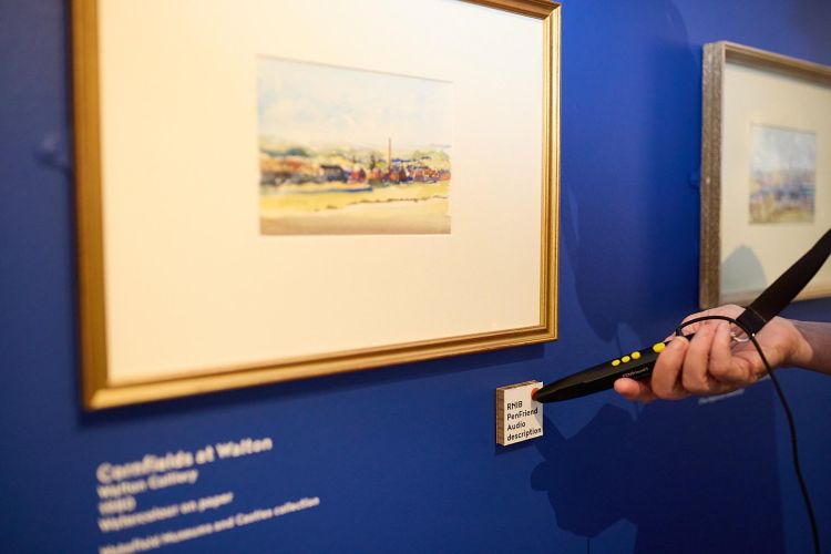 Visitor to an exhibition listens to an audio description of a painting using an RNIB PenFriend