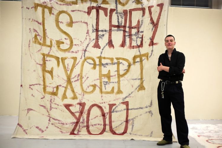 Artist George Storm Fletcher next to text based artwork