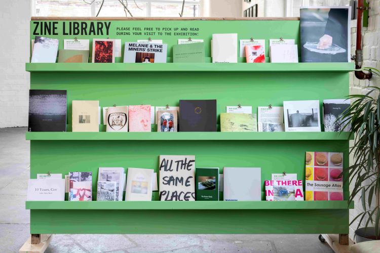Zine library at Sunny Bank Mills. A range of zines are housed on a green book case of three shelves