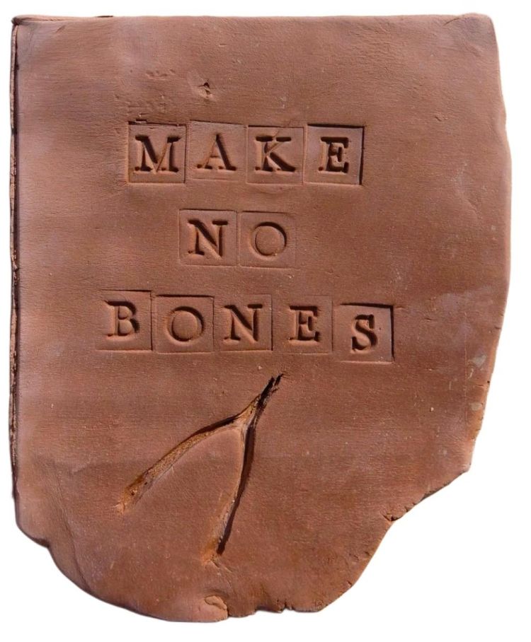 Slab of clay with the words make no bones pressed into it
