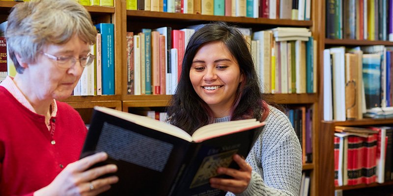 Student and tutor sharing a book.