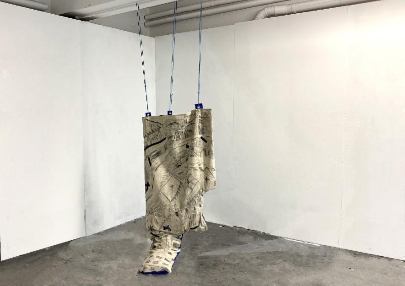 Sculpture by Molly Newham in a gallery space, materials such as tarp, canvas, charcoal, graphite, bail twine and electrical tape