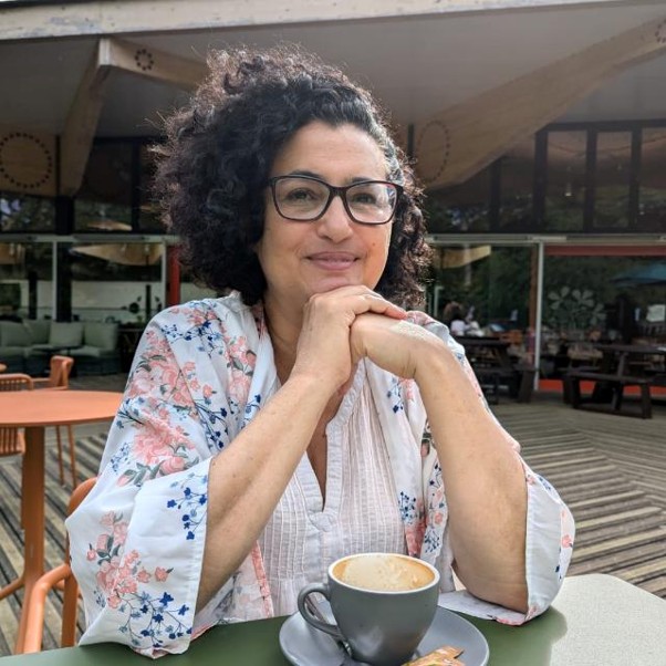 A woman sitting at an outdoor table with a flat white