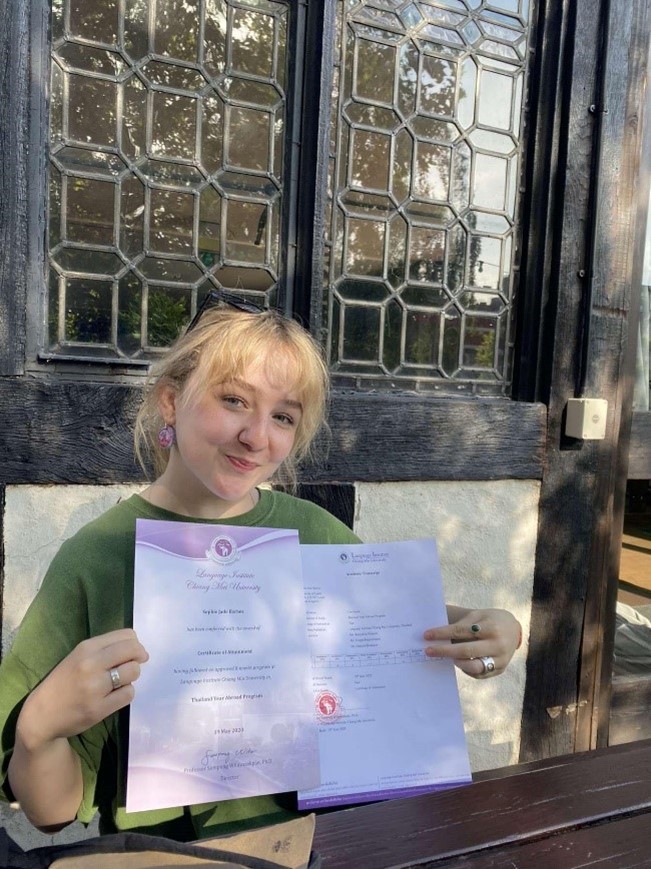 Person sat on a bench holding two certificates