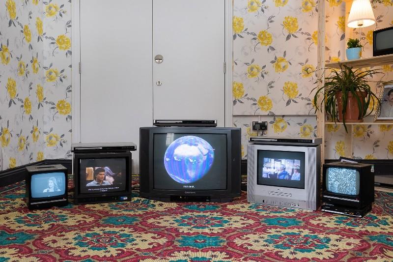 Art installation including TVs and rug by Suman Shams