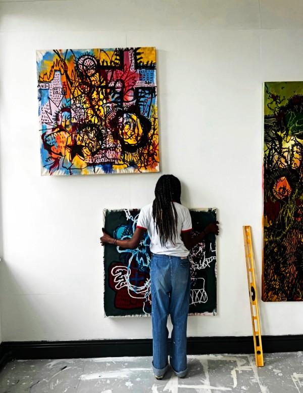 Tianna McIntosh installing some of her paintings, in preparation for the Can you let us in? BA Fine Art Degree Show, June 2023. 