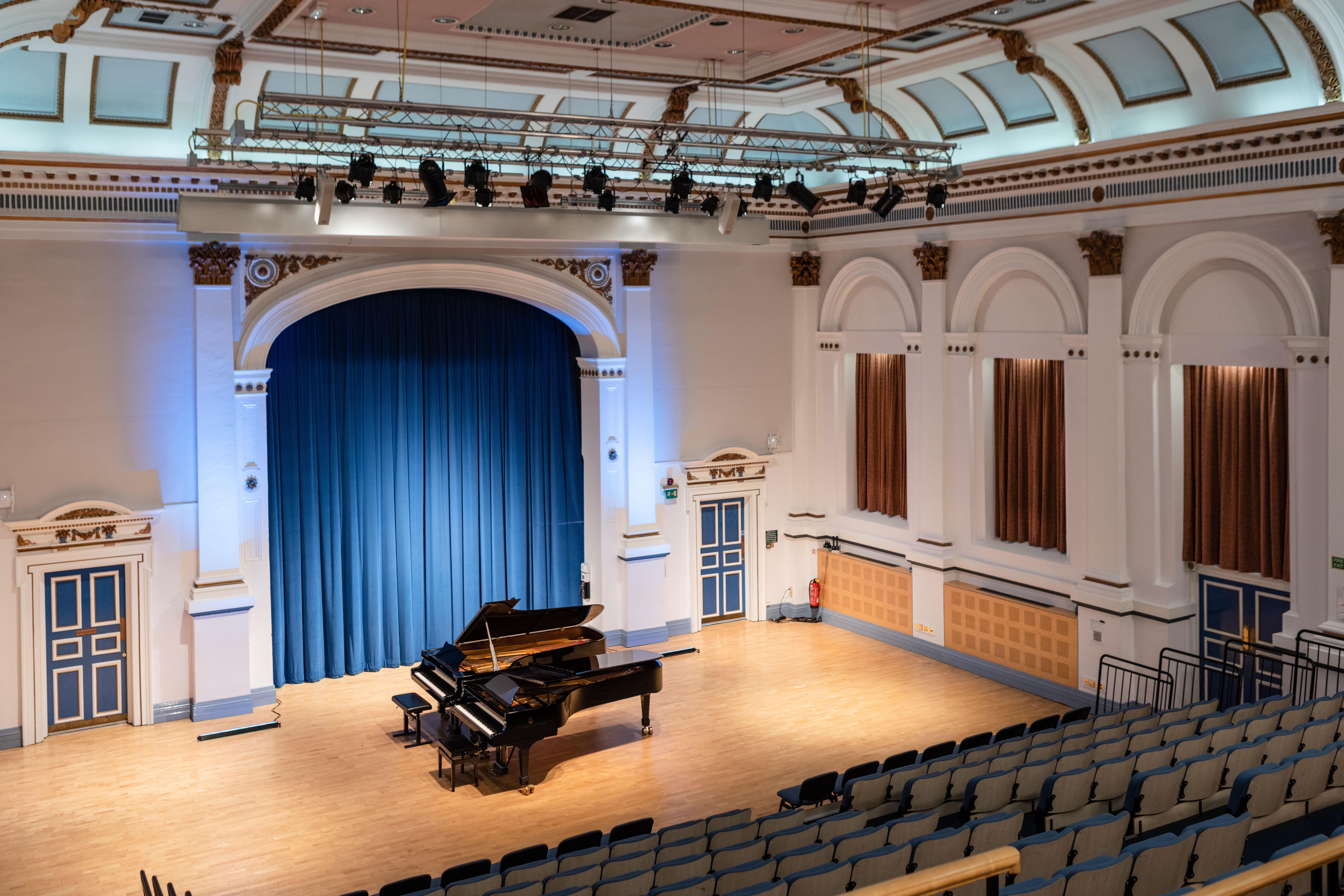 Image from balcony of the Concert Hall showing seating, stage area, pianos and lighting.