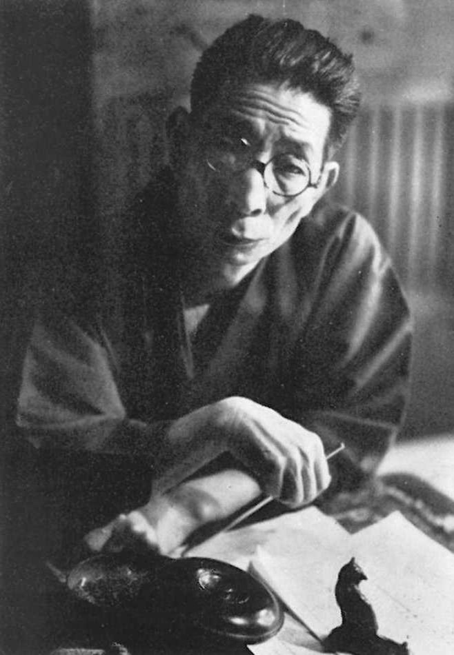 An old black and white photo of a Japanese man at his desk