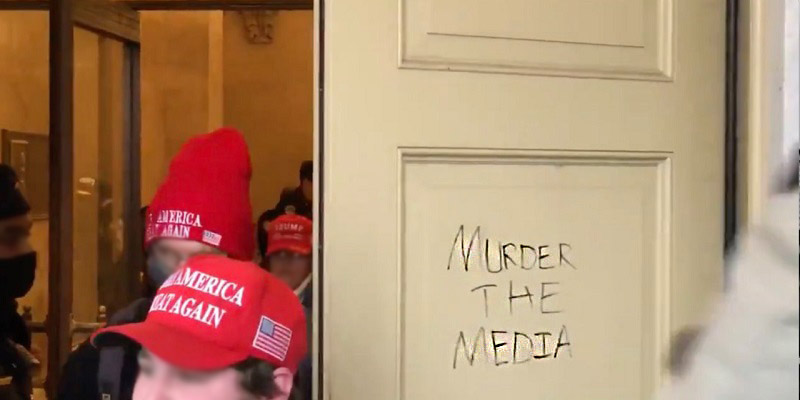 People in red baseball caps next to door with grafitti syaing Murdee the Media