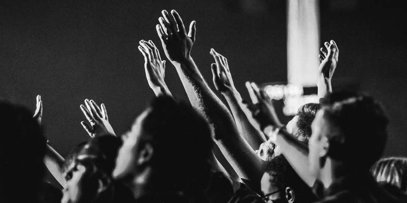 Monochrome image of hand and arms of crowd at music event
