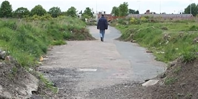 Man walking down a grassy road.