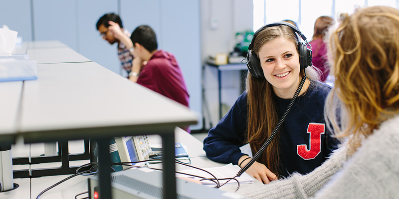 Students using headphones at desks.