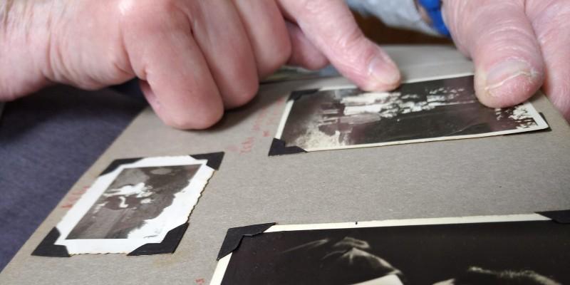 Photo of hands of a person pointing at photos in an album