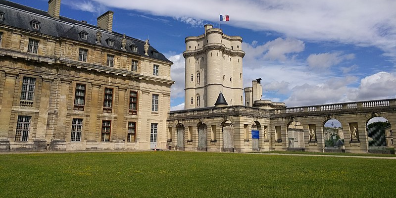 A French chateau against a blue sky with a green grass lawn.