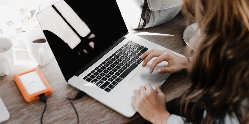 Woman on laptop with phone charging