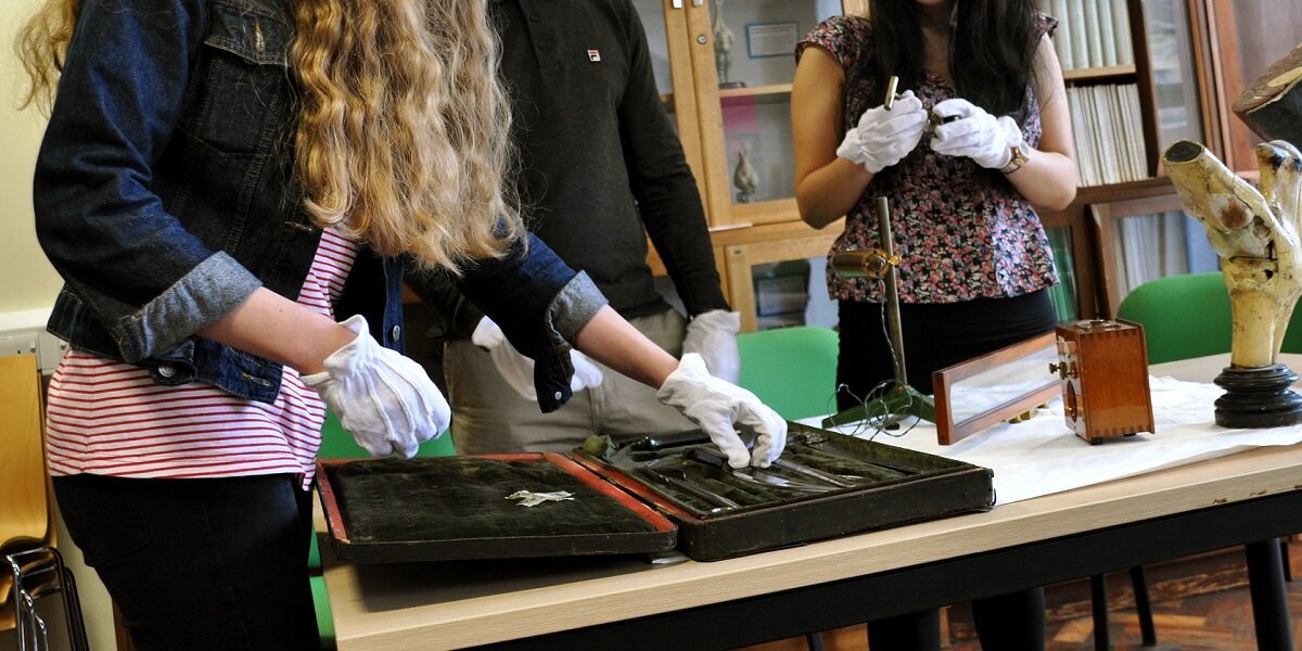 Students wearing protective gloves handling artefacts