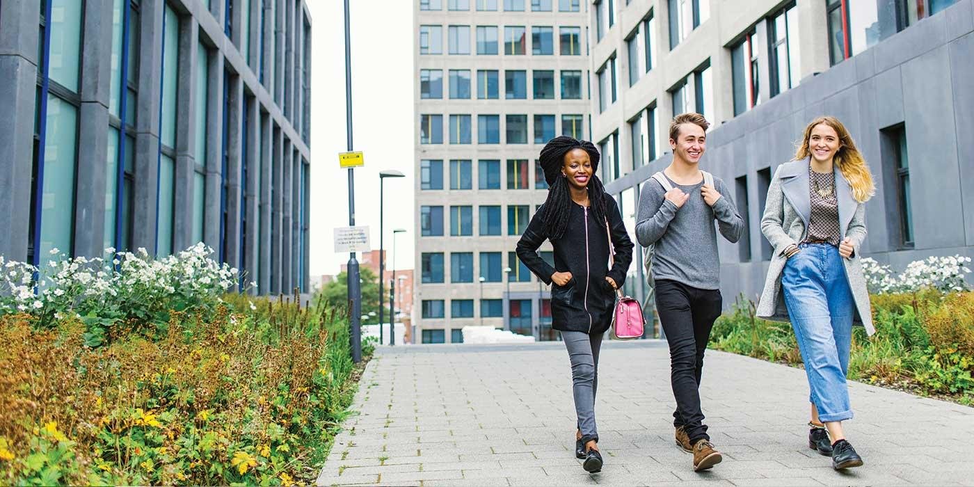 Three students walking through the exterior of Central Village accommodation.