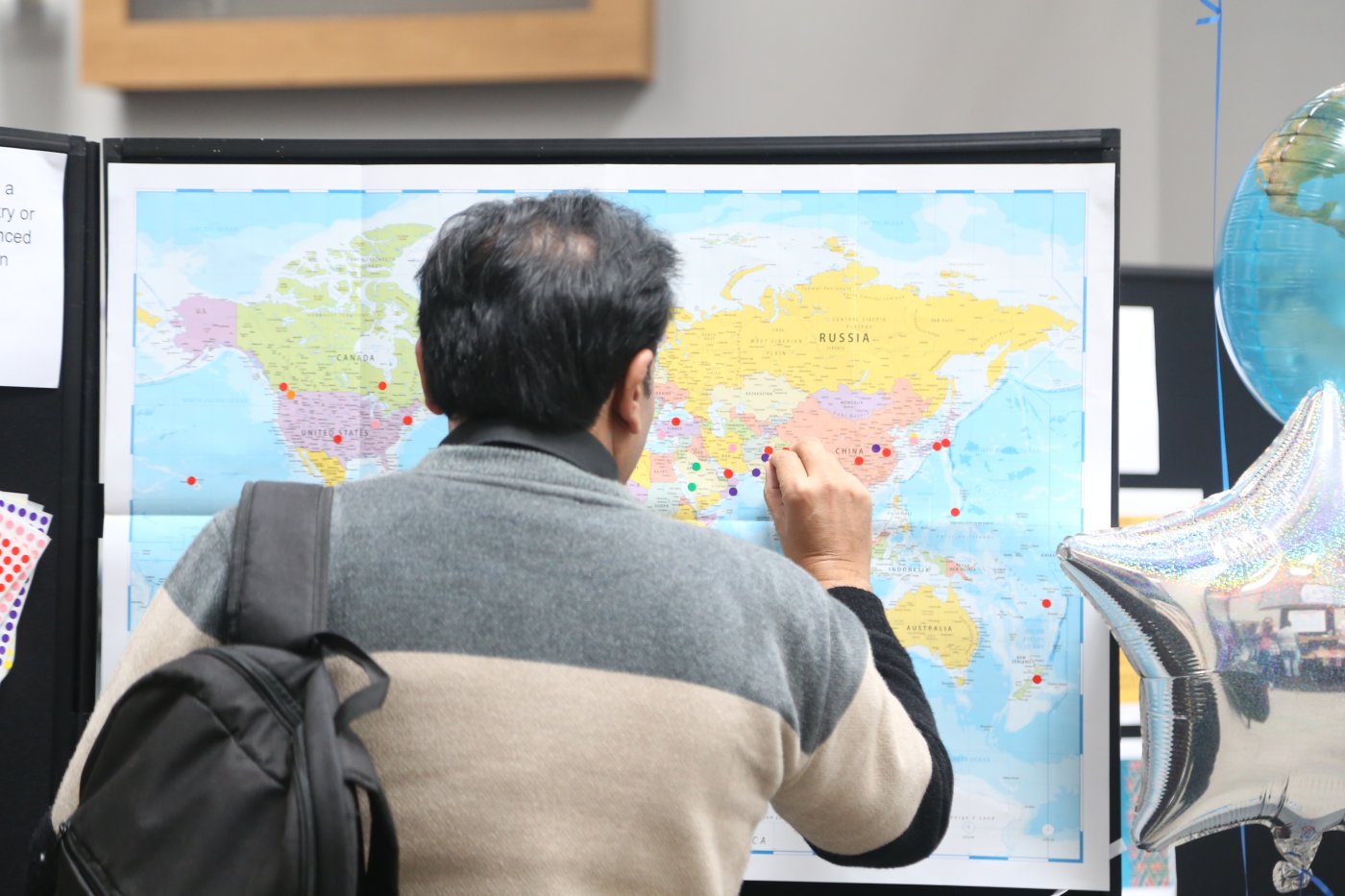 A man places a pin in a map of the world