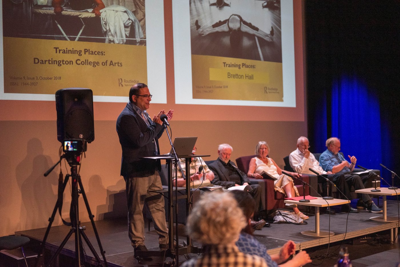 A speaker and panel in front of an audience