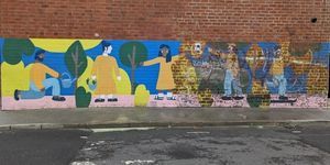 A long, colourful outdoor wall mural featuring people and trees
