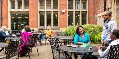 Postgraduate researchers sitting around tables outside Baines Wing