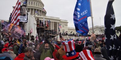 A crowd of people with American flags storm the US Capitol building