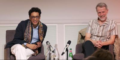 Two people sit on chairs on a stage
