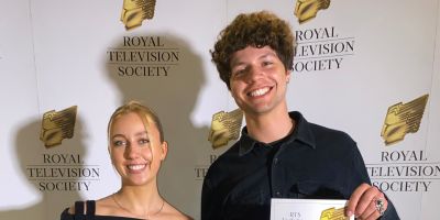 Evie and Taylor smiling into the camera with Royal Television Society background