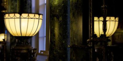An electrified Chippendale torch&egrave;re and its reflection in a mirror in a dark room of Harewood House.