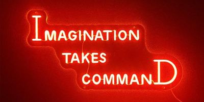 Light installation with the words imagination takes command on a red background