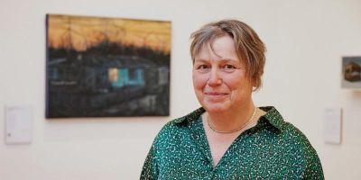 Judith Tucker next to one of her paintings at the opening of Arcadia for All in The Stanley and Audrey Burton Gallery.