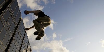 A man jumps from one building to another, demonstrating parkour in action