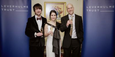 Dr Ross Cole, Dr Nahal Khabbazbashi and Prof Matthew Treherne at the Leverhulme Gala Dinner. Blue Leverhulme Trust banners are at either side of them.