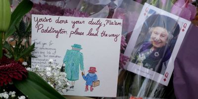 A picture of flowers, a picture of Queen Elizabeth II and a picture of Paddington Bear and Queen Elizabeth left as part of tributes laid following her death, 
Picture free to use via Wikimedia Commons/Doyle of London
