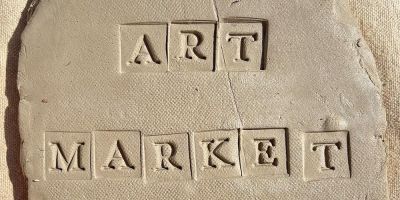 Letters spelling ART MARKET pressed into clay on a canvas background