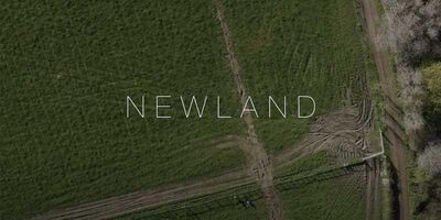 A birds-eye view shot of the farm that features in the film with the film title 'Newland' across the screen.