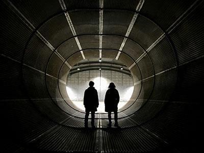 Two people standing in a cold war era bunker with their backs to the camera