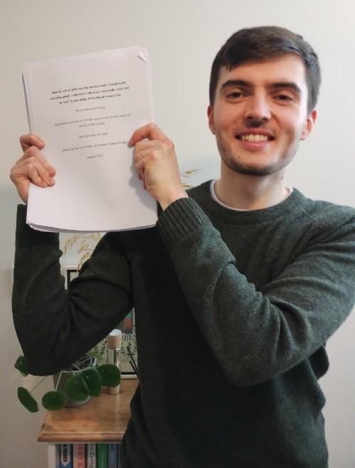 Person holding up a printed doctoral thesis