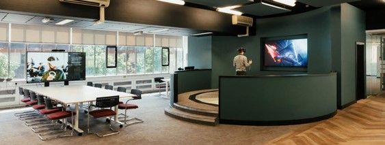 A man with a Virtual Reality headset on his face stands in a big room