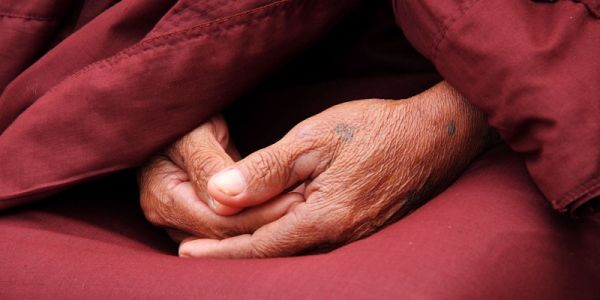 Hands folded in lap of Buddhist monk robes
